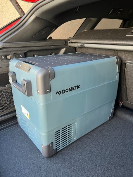 Blauer Kühlbox der Marke Dometic im Kofferraum eines Fahrzeugs.