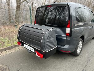 Kofferraum eines grauen Fahrzeugs mit abgedecktem Gepäckträger auf der Rückseite.