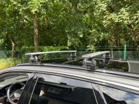 Dachträger eines Autos, montiert auf einem grauen Fahrzeug, umgeben von Bäumen.