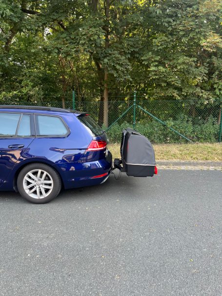 Blauer Kombi mit aufgeklapptem Fahrradträger auf der Straße.