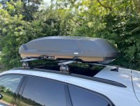 Dachbox auf einem silbernen Auto, platziert auf dem Dachträger.