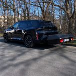Schwarzer SUV parkt an einer Straße, umgeben von Bäumen.