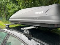 Dachbox auf dem Auto, montiert auf einem Dachträger, bei bewölktem Wetter.