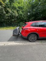 Rotes SUV mit einem grauen Gepäckträger auf der Heckklappe.