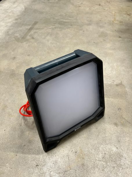 Tragbare LED-Arbeitsleuchte mit grauem Gehäuse und rotem Kabel.